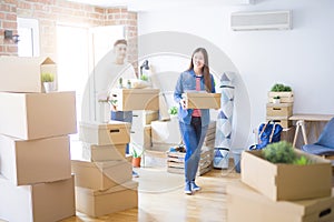 Beautiful young asian couple looking happy holding cardboard boxes, smiling excited moving to a new home