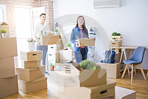 Beautiful young asian couple looking happy holding cardboard boxes, smiling excited moving to a new home