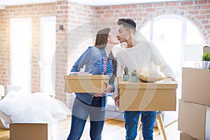 Beautiful young asian couple looking happy holding cardboard boxes, smiling excited moving to a new home