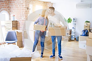 Beautiful young asian couple looking happy holding cardboard boxes, smiling excited moving to a new home