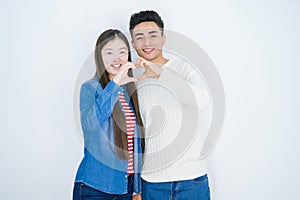 Beautiful young asian couple over white isolated background smiling in love showing heart symbol and shape with hands