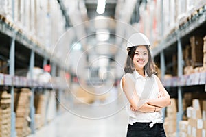 Beautiful young Asian engineer or technician smiling, warehouse or factory blur background, industry or logistic concept