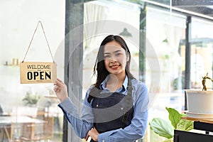 Beautiful young Asian female coffee shop owner or barista standing in front of the entrance