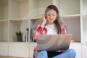 Beautiful young Asian female college student studying on online class, using laptop computer