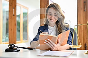 A beautiful young Asian female lawyer notes something on her personal book