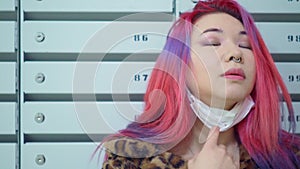 Beautiful young asian girl colored hair medical mask near mailboxes