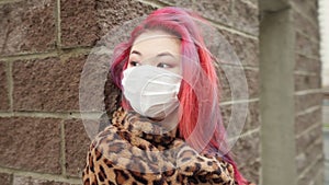 Beautiful young asian girl with colored hair in medical mask standing street