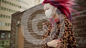 Beautiful young asian girl with colored hair in medical mask walk street.