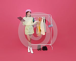 beautiful young Asian teen seller woman selling fashion clothes isolated on pink background. SME online store social e-commerce