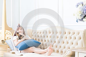 Beautiful young Asian Thai woman was lying on the sofa with his cat happily and stroking the cat`s head with love.