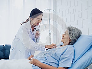 A beautiful young Asian woman doctor in white suit smiled while using stethoscope to examine.