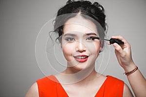 Beautiful young asian woman doing makeup using mascara on her eyelashes
