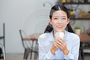 Beautiful young asian woman drinking coffee and smile in the morning at cafe, girl sitting in coffee shop for breakfast and leisur