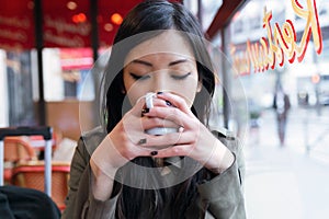 Beautiful young asian woman drinking coffee in the terrace of a coffee shop.