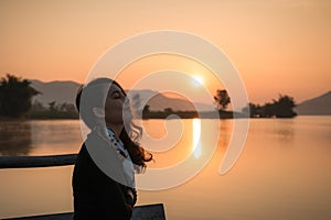 Beautiful young asian woman enjoying with sunrise on mountain lake