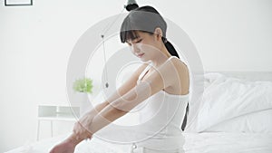 Beautiful young asian woman happy applying cream or lotion with moisturizer to skin on arm.