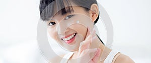 Beautiful young asian woman happy applying cream or lotion with moisturizer to skin on face.