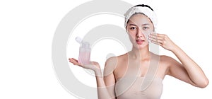 Beautiful young asian woman hold toner bottle and using cotton pad and cleaning her face, apply it to beauty face for firming