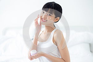 Beautiful young asian woman holding cartridge applying cream or lotion with moisturizer to skin on face.