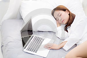 Beautiful young asian woman with laptop lying down in bedroom, girl tired sleep with computer notebook.