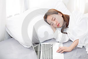 Beautiful young asian woman with laptop lying down in bedroom, girl tired sleep with computer notebook.