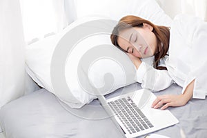 Beautiful young asian woman with laptop lying down in bedroom, girl tired sleep with computer notebook.