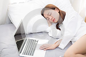 Beautiful young asian woman with laptop lying down in bedroom, girl tired sleep with computer notebook.