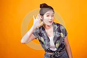 Beautiful young Asian woman listen to something in tropical shirt