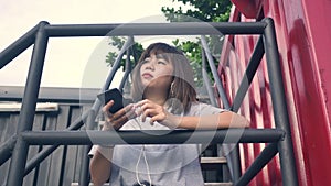 Beautiful young asian woman listening to music on a smart phone in the city. Young asian woman relaxing listening to music.