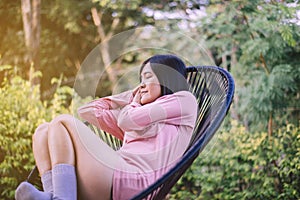 Beautiful young asian woman lying down with hands on her head and sleeping on modern chair at nuture,Relaxing time,Happy and smili
