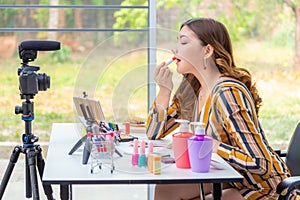 Beautiful young Asian woman making online product review at home