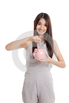 Beautiful young Asian woman with piggy bank and coin
