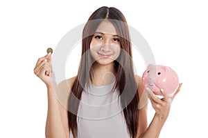 Beautiful young Asian woman with piggy bank and coin