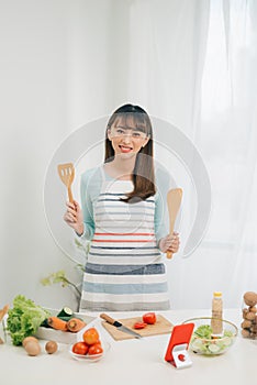 Beautiful young asian woman reading cooking recipe or watching show while making salad