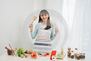 Beautiful young asian woman reading cooking recipe or watching show while making salad