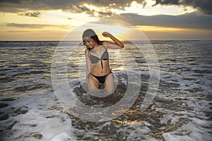 and beautiful young Asian woman relaxing playful at sunset beach kneeling on water