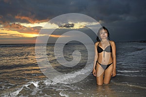 and beautiful young Asian woman relaxing playful at sunset beach kneeling on water