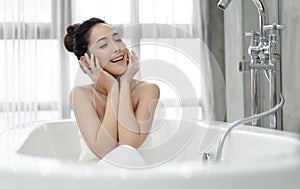 Beautiful young Asian woman relaxing sitting in the bathtube in the bathroom.Spa treatments for beauty and health with skin care