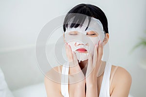 Beautiful young asian woman with sheet facial mask at home, beauty girl applying cosmetic and makeup with skin care.