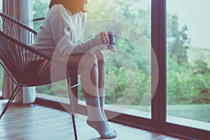 Beautiful young asian woman sitting on chair and drinking a cup of coffee in bedroom at home,Enjoys of resting time