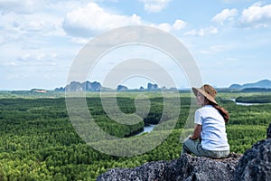 A beautiful young asian woman sitting on the mountain peak while traveling the mangrove forest viewpoint