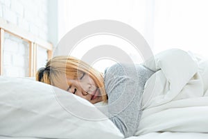 Beautiful young Asian woman sleeping in bed in the morning.