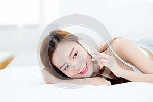 Beautiful young asian woman smiling lying and relax on the bed in the morning, girl using mobile smart phone talking enjoy