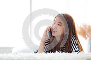 Beautiful young asian woman smiling lying relax on the bed in the morning, girl using mobile smart phone talking enjoy,