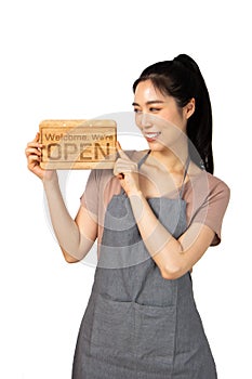 Beautiful young asian woman smiling pretty teeth wearing a apron.Woman holding a wooden sign pointing and thumbs up