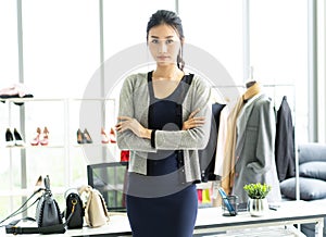 Beautiful young Asian woman standing with crossed arms in front in clothes shop looking to camera. Startup Small Business Owner