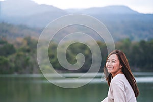 A beautiful young asian woman standing in front of the lake and mountains