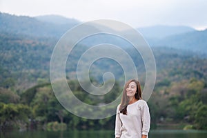 A beautiful young asian woman standing in front of the lake and mountains