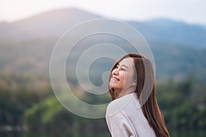 a beautiful young asian woman standing in front of the lake and mountains