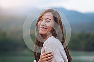 A beautiful young asian woman standing in front of the lake and mountains